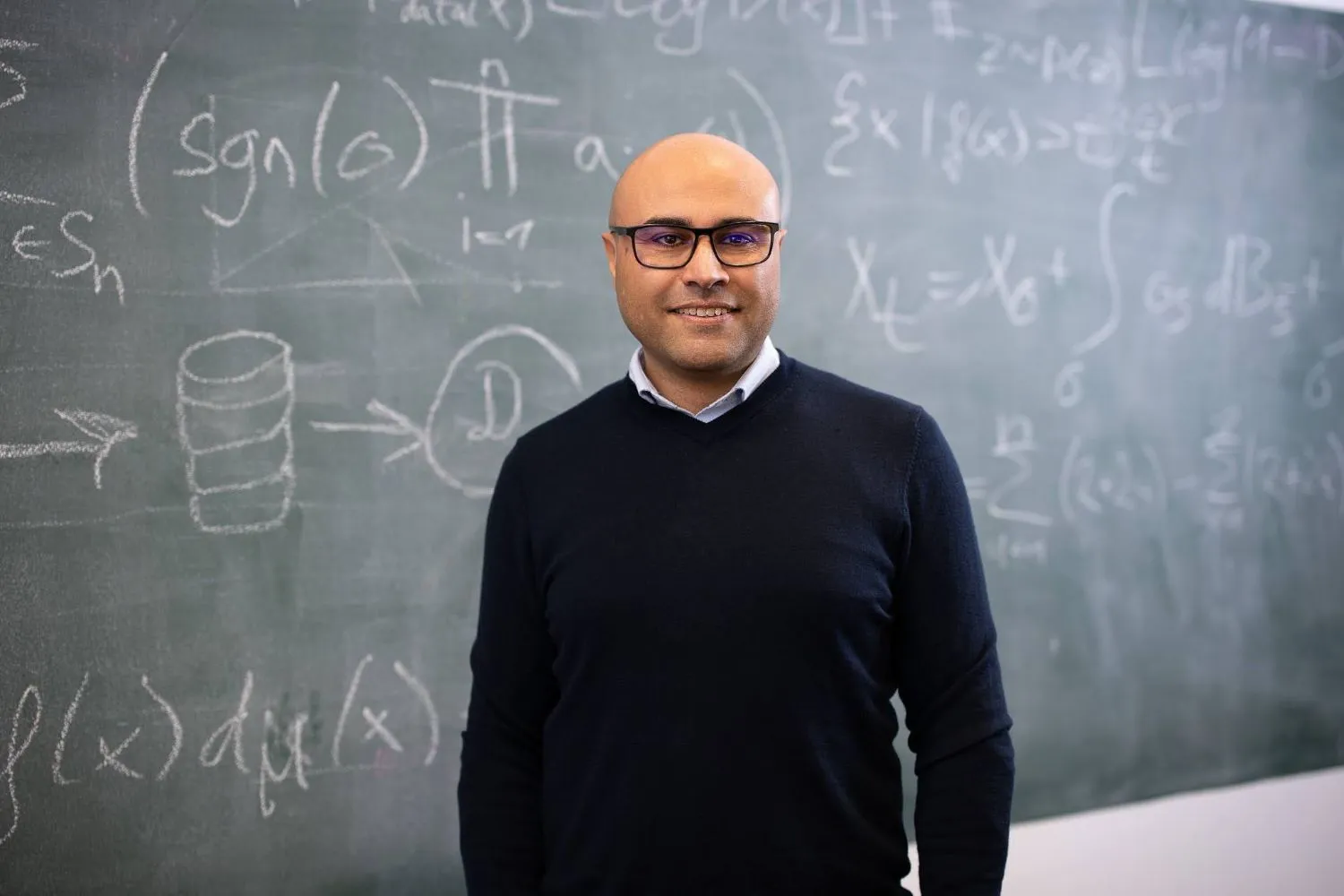 Iman Soltanzadeh in front of a chalkboard full of equations.